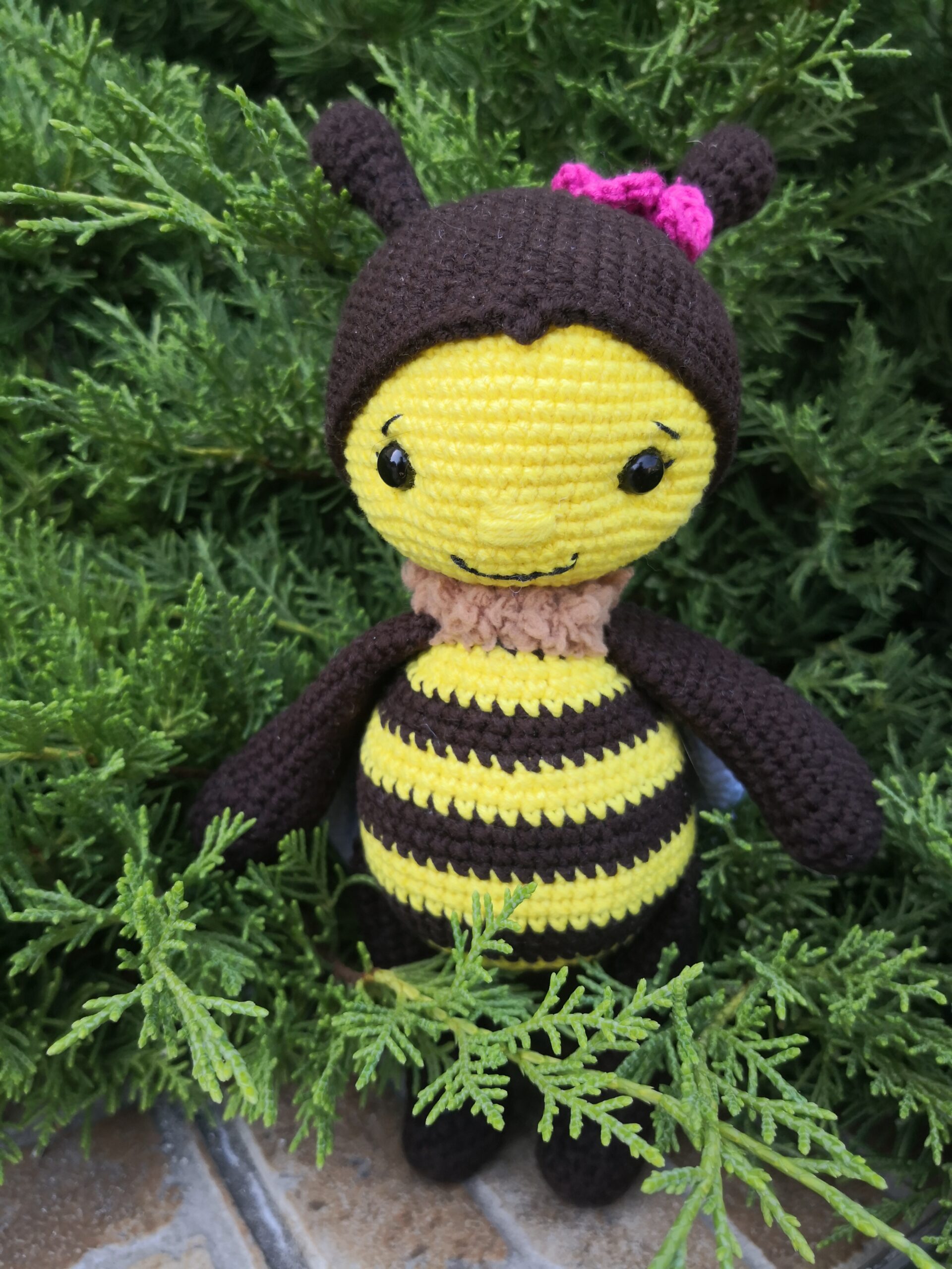 Handmade crocheted bee with pink flower on its head.