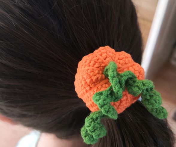 "Little girl proudly wearing the crochet pumpkin hairband in her hair.