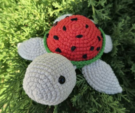 Full view of the crochet watermelon turtle with vibrant red shell and black seed details.